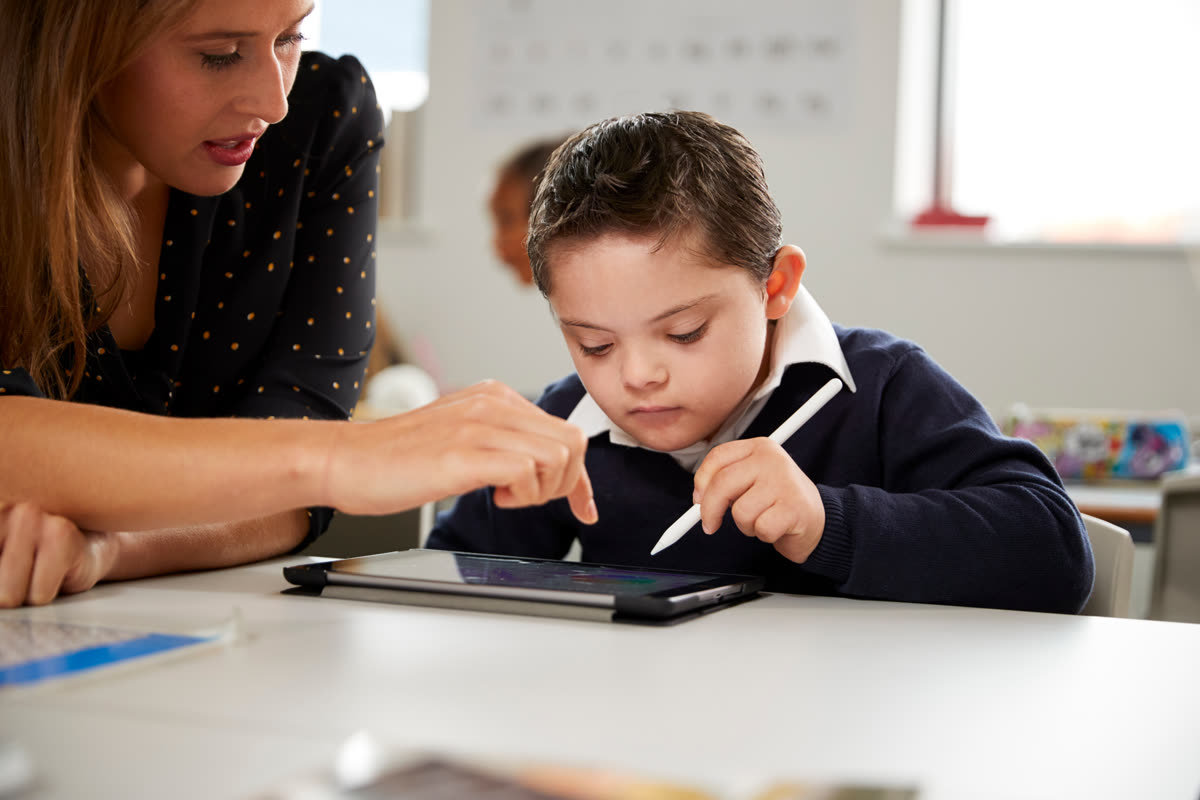 A teacher helping a pupil with a tablet