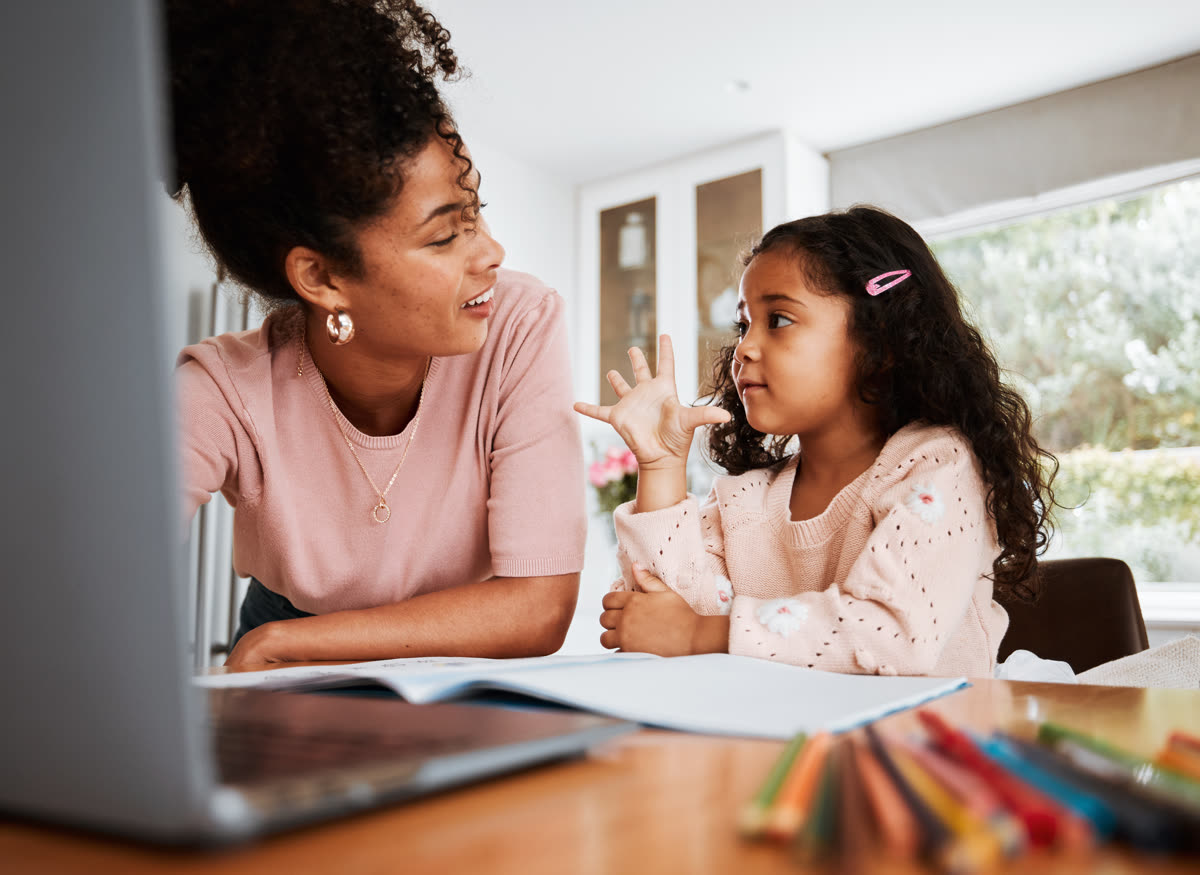 A parent talking with their child at a desk