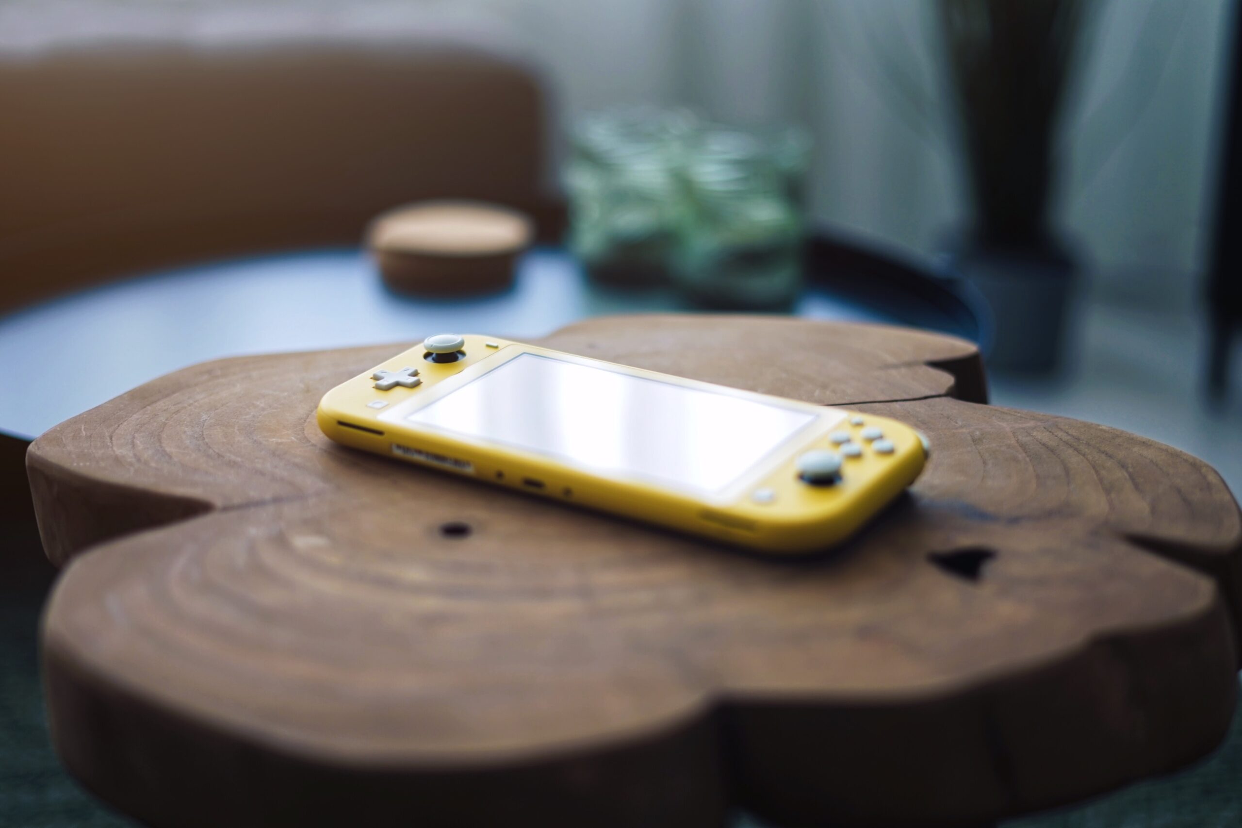 A yellow handheld games console resting on a wooden table.