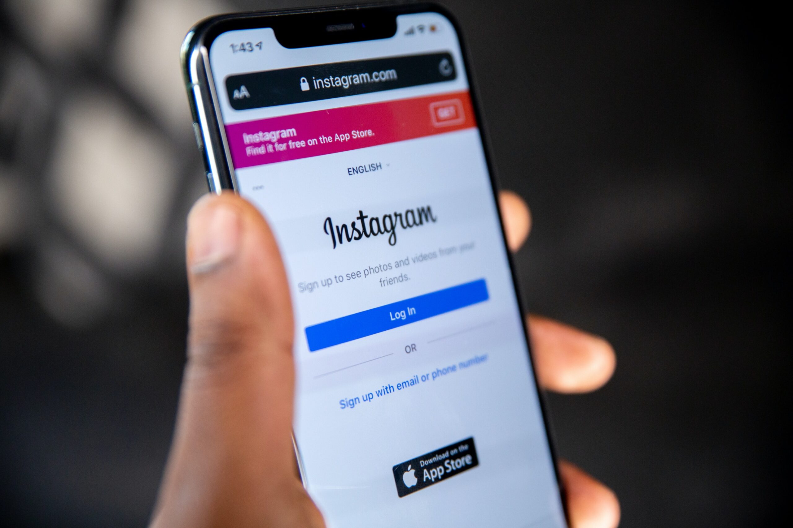 A hand holding a mobile phone showing the Instagram login screen.